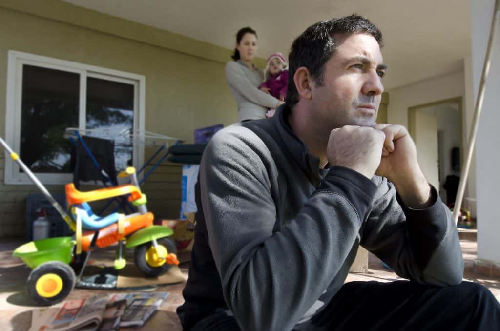 How does Social Environment Affect Health? A man sits on his porch depressed while his wife and child watch him at a distance.