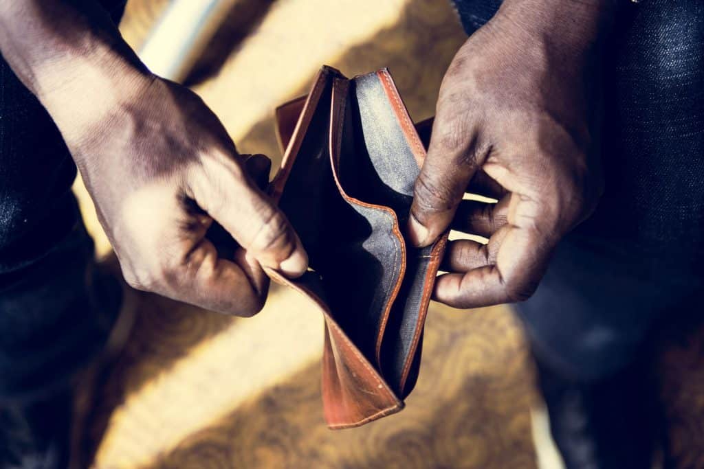 How does Social Environment Affect Health? A man's hands hold open an empty wallet. 